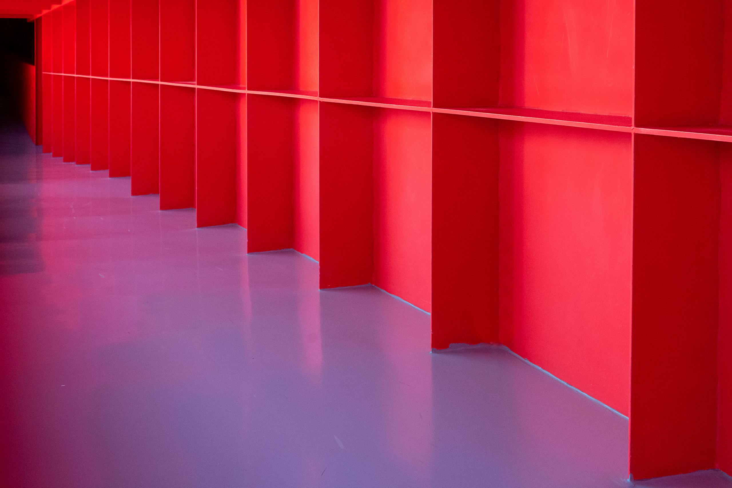 A vibrant red corridor showcasing modern architectural design and symmetry.