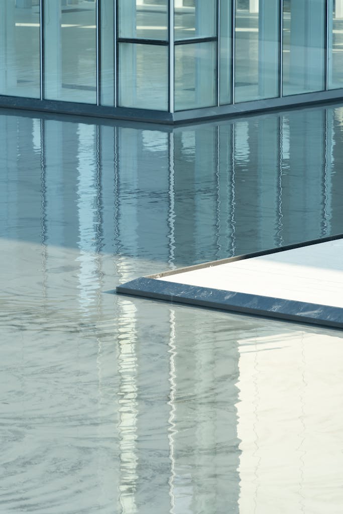 Abstract view of a modern glass building reflecting in a calm water surface, showcasing architectural elegance.