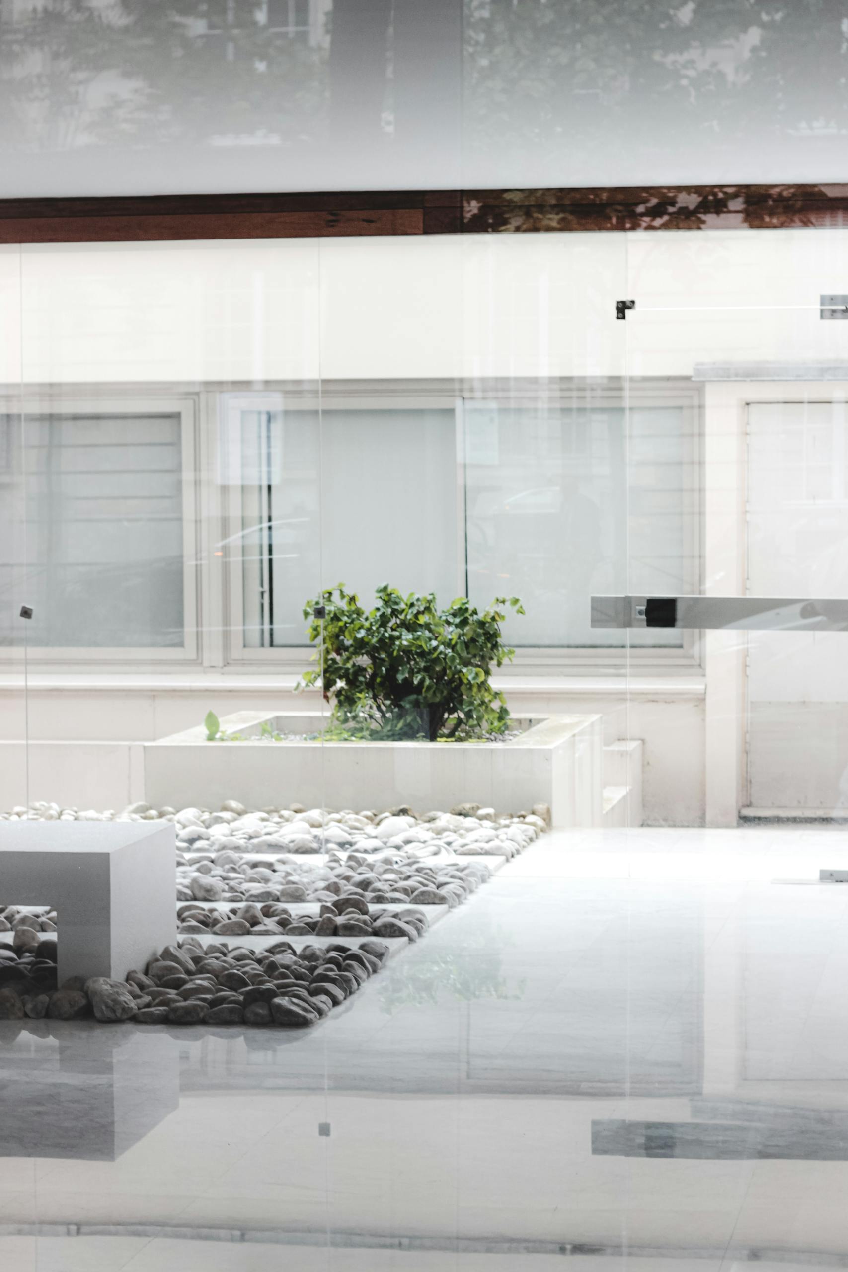 Bright and airy modern patio with white decor, pebbles, and a potted plant for a tranquil setting.