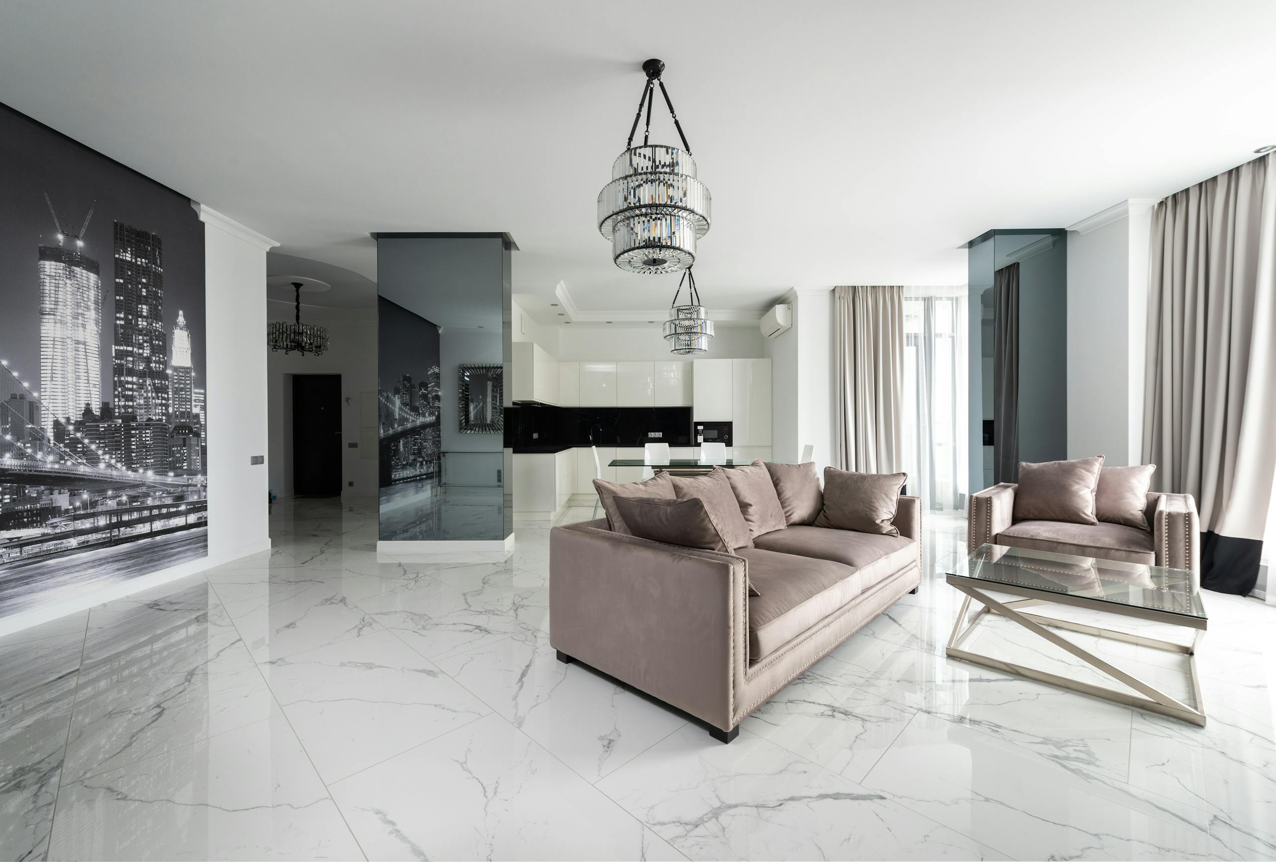 Spacious and elegantly decorated modern living room featuring luxury furniture and chic chandeliers.